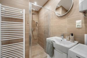 a bathroom with a shower and a sink and a mirror at Apartmány Centrum Trenčín - Greenyard in Trenčín