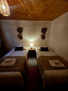 a room with two beds and a lamp on the wall at Hostal Desert in San Pedro de Atacama