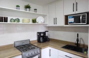 a kitchen with a stove top oven next to a microwave at Bello loft studio en el corazón de Tijuana in Tijuana