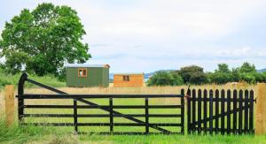 a fence in a field with a small house at Yurt Ash tree in Saint Briavels