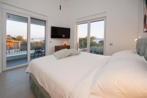 a white bedroom with two beds and a balcony at Villa Marcello in Zadar +26 photos