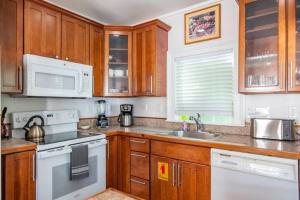 a kitchen with wooden cabinets and white appliances at Turtle Nest Condo - Pool - 2nd Floor in Key West +13 photos