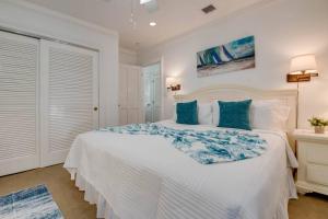 a white bedroom with a large bed with blue pillows at Turtle Nest Condo - Pool - 2nd Floor in Key West