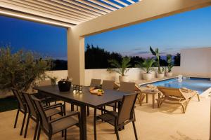 a dining room with a table and chairs and a pool at Villa Marcello in Zadar