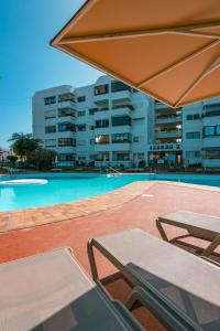 a swimming pool with two chairs and a table at Apartamento Yumbo Iguazu Luxury in Maspalomas