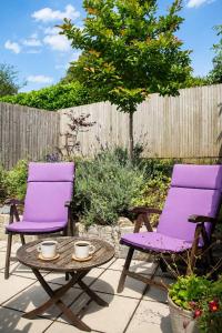 two purple chairs and a table on a patio at Meadowvine - By Rowes Retreats in Penryn
