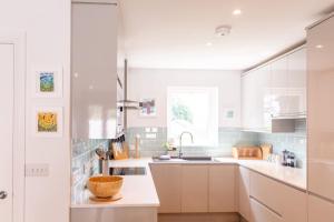 a kitchen with white cabinets and a bowl on the counter at Meadowvine - By Rowes Retreats in Penryn