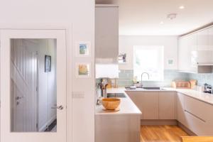 a kitchen with white cabinets and a bowl on a counter at Meadowvine - By Rowes Retreats in Penryn +61 photos