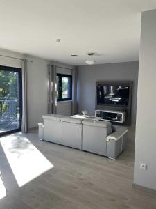 a living room with white couches and a flat screen tv at WidziMisie Summer Apartament in Dominice