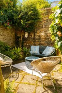 three chairs and a table in a garden at Tide View Townhouse - By Rowes Retreats in Falmouth