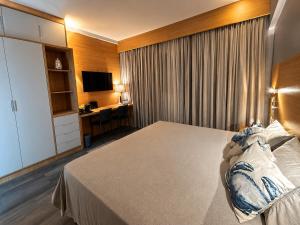 a hotel room with a bed with a desk and a television at Flat em Santos próximo a praia e Vila Belmiro in Santos
