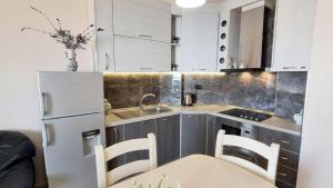 a kitchen with white cabinets and a table and chairs at Marina Chic Apartment in Vlorë