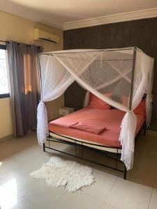 a bedroom with a bed with a mosquito net at Soleil ak Jàmm in Mbour