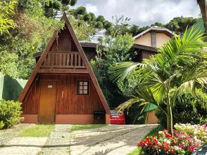 a wooden house with a porch and flowers in front of it at Chalé - Sossego 1 in Campos do Jordão