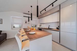 a kitchen with a wooden table and white cabinets at Apartments Separovic in Prizba