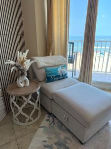 a bedroom with a bed and a table and a balcony at Boardwalk Oceanfront Condo with Panoramic Views in Virginia Beach