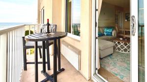 a balcony with a table with a bottle of wine on it at Boardwalk Oceanfront Condo with Panoramic Views in Virginia Beach