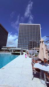 a building with a pool and a table and an umbrella at Salinas Beach Resort in Salinópolis