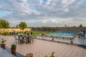 a group of people sitting around a table by a pool at Sand Dunes Stay in Bagru
