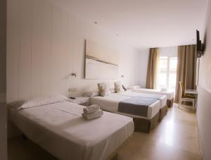 a hotel room with three beds and a window at Hotel Oasis in Córdoba