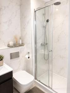 a white bathroom with a shower and a toilet at Luxury Central Solihull Apt - King Bed, Sofa Bed & 2 Parking Spaces in Solihull