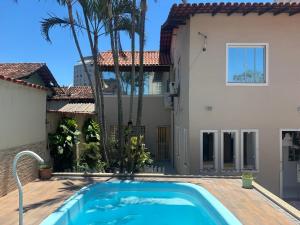 a villa with a swimming pool in front of a house at Casa Costa do Sol completa, 100m da praia in Macaé