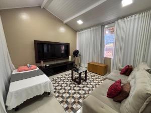 a living room with a couch and a flat screen tv at Casa Costa do Sol completa, 100m da praia in Macaé