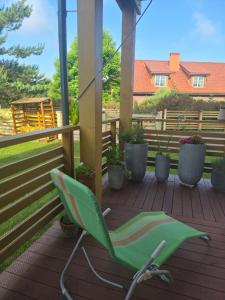 a green rocking chair sitting on a porch at Butas Karklėje in Karklė