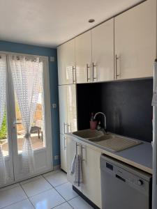 a kitchen with white cabinets and a sink and a window at Villa playa in Valras-Plage +3 photos