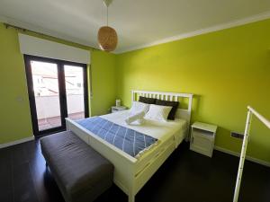 a bedroom with a bed with green walls and a window at Cascais House - Pool in Parede
