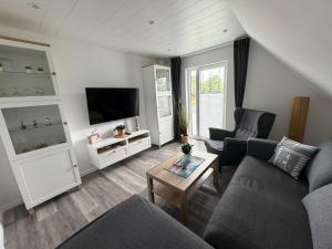 a living room with a couch and a tv at Haus Mariechen in Hooksiel