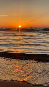 a sunset on a beach with the ocean at Sunny House Baltic in Kopalino +12 photos
