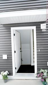 an open door on a gray house with flowers at The Ivory house in Prince George