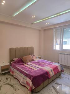 a bedroom with a large bed with a purple blanket at Apparemment valmascort annaba in Annaba