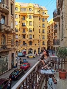a woman sitting at a table on a balcony overlooking a city at Sydney DownTown-Cairo in Cairo