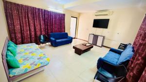 a living room with a bed and a tv and chairs at Tranquil villa Raichak in Diamond Harbour