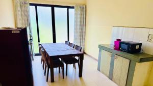 a kitchen with a table with chairs and a microwave at Tranquil villa Raichak in Diamond Harbour