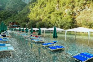 a bunch of beach chairs and umbrellas in the water at Gio Camping Shala River in Mollʼ e Shoshit