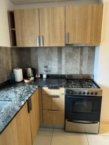 a kitchen with a stove and wooden cabinets at Monoambiente in Venado Tuerto