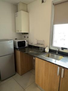 a kitchen with a sink and a refrigerator and a microwave at Monoambiente in Venado Tuerto