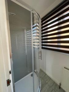 a glass shower in a bathroom with a window at The Nook in Bedford