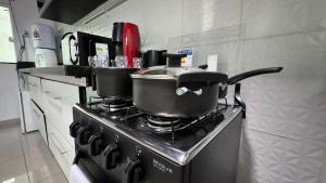 two pots on top of a stove in a kitchen at Apartamento com piscina privativa 7 minutos da basílica in Aparecida