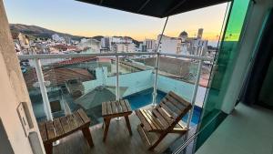 two chairs on a balcony with a view of a city at Apartamento com piscina privativa 7 minutos da basílica in Aparecida