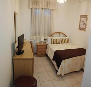 a bedroom with a bed and a desk with a television at Hostal La Madrileña in La Gudiña