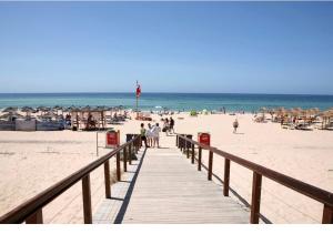a boardwalk leading to a beach with people on it at Marachique Beach Flat in Alvor