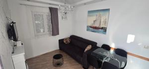 a living room with a black couch and a boat painting at Pool, Sauna, Jacuzzi with Sea view - Apartment Josipa in Podstrana