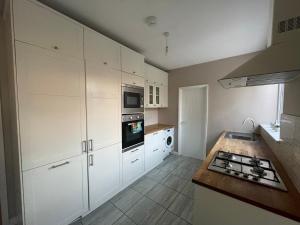 a kitchen with white cabinets and a stove top oven at The Nook in Bedford