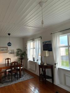 a dining room with a table and chairs and windows at Seaside Retreat, Glacier View in Hellissandur
