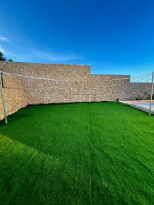 a brick wall with a green field of grass at ڤيلا الكرم in Jerash