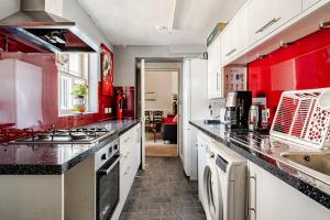 a kitchen with red walls and white cabinets at Edinburgh Beach in Edinburgh